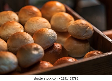 Close-up hot Fresh Baked Bread Rolls in a wooden box for the customer, the stack of freshly baked bread rolls, warm light from above.