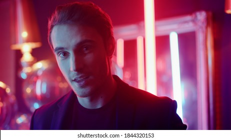 Closeup Hot Man Looking At Camera In Nightclub. Portrait Of Playful Man Sending Air Kiss On Neon Lights Background. Romantic Man Laughing At Club Party.