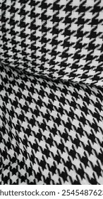 A close-up of a houndstooth pattern fabric in black and white. The intricate pattern creates a visually appealing texture and adds a touch of classic elegance to any design.