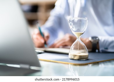 Close-up Of Hourglass In Front Of Businessperson's Hand Calculating Invoice - Shutterstock ID 2178996015