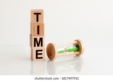 Close-up of an hourglass next to wooden blocks with the text time. White backround. - Shutterstock ID 1817497931