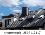 Close-up house retro roof panel with standing seam and fasteners. Classic style black metal panel with rebate joint. Modern galvanized steel roofing sheet with ribs. Falz roofing. Building