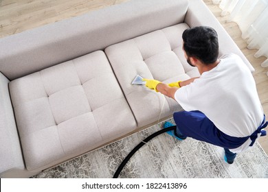 Close-up Of Housekeeper Holding Modern Washing Vacuum Cleaner And Cleaning Dirty Sofa With Professionally Detergent. Professional Springclean At Home Concept