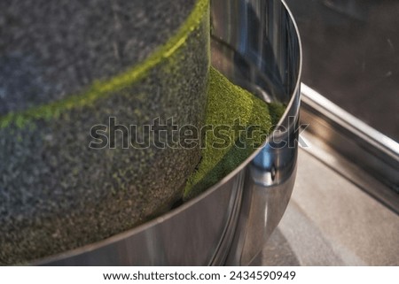 closeup of how-to Japanese Matcha Tea Mill Stone or Matcha green tea grinding stone machine in motion in factory or Japanese tea shop.