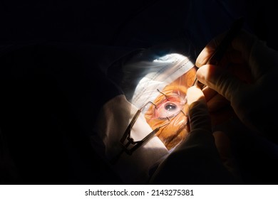 Close-up Of A Human Eye, Cataract Surgery In An Ophthalmology Operating Room. Sterile Drape And Surgeon's Hands With Sterile Gloves Inserting A Cataract Forceps Into The Anterior Chamber Of The Eye.