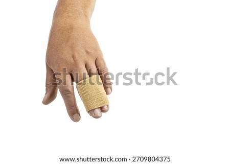 Close-up of a human hand with a beige elastic bandage wrapped around the middle and ring fingers, isolated on a white background. The hand is relaxed and the fingers are slightly bent.