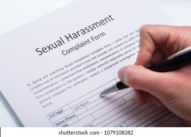 Close-up Of A Human Hand Filling Sexual Harassment Complaint Form With Pen
