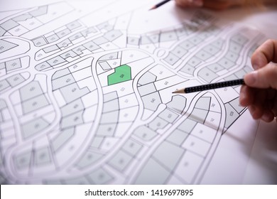 Close-up Of Human Hand Holding Pencil Over Paper Cadastre Map - Shutterstock ID 1419697895