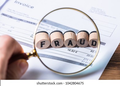 Close-up Of A Human Hand Looking At Fraud Blocks Through Magnifying Glass On Invoice - Shutterstock ID 1042804675