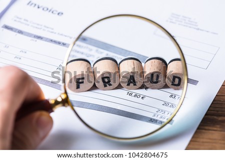 Close-up Of A Human Hand Looking At Fraud Blocks Through Magnifying Glass On Invoice