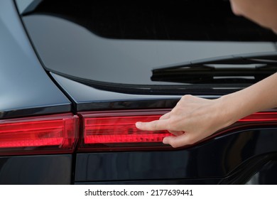 Close-up of human hand on rear car stoplight, checkout before driving. Safety travel concept - Shutterstock ID 2177639441