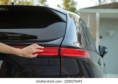 Close-up of human hand on rear car stoplight, checkout before driving. Safety travel concept - Shutterstock ID 2200270491