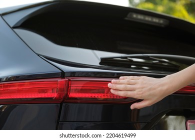 Close-up of human hand on rear car stoplight, checkout before driving. Safety travel concept - Shutterstock ID 2204619499