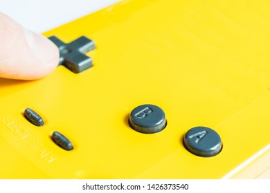 Close-up of a human hand pressing with the index finger the black button of a yellow video game joystick