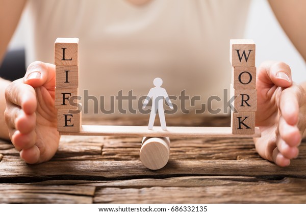 Close-up Of A Human Hand Protecting Balance
Between Life And Work On
Seesaw