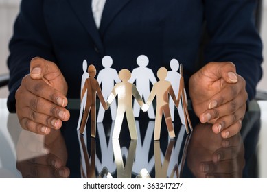 Close-up Of Human Hand Protecting Cut-out Figures - Powered by Shutterstock