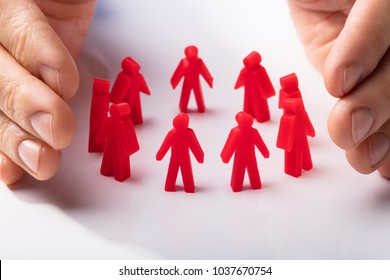 Close-up Of A Human Hand Protecting Red Human Figures On White Background