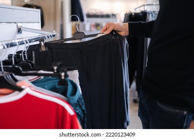 Close-up Of Human Hand Take Clothes To Try On. Male Hand Take Pajamas In Clothing Store