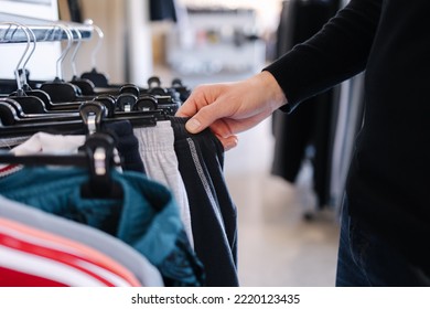 Close-up Of Human Hand Take Clothes To Try On. Male Hand Take Pajamas In Clothing Store