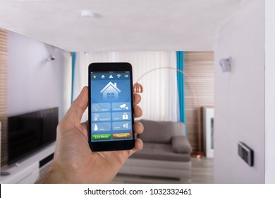 Close-up Of Human Hand Using Smart Home System On Smartphone In Living Room