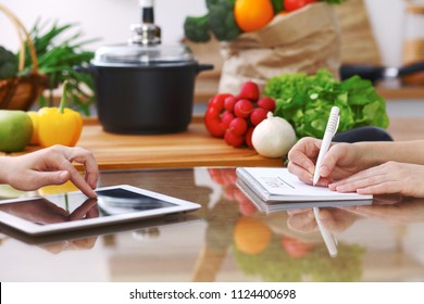 Closeup of human hands cooking in kitchen using touch pad. Women discuss a menu. Healthy meal, vegetarian food and lifestyle concept - Shutterstock ID 1124400698