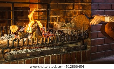 Closeup of human hands at fireplace making fire with bellows. Person heating warming up and relaxing. Winter at home.