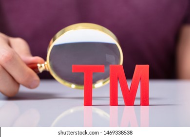 Close-up Of Human Hand's Holding Magnifying Glass Looking Red Trademark Tm Icon