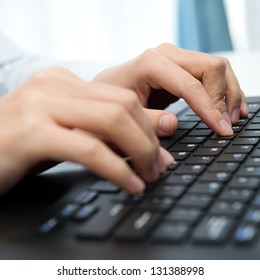 Close-up of human hands working on laptop.