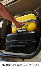 Closeup image of airport transfer driver taking suitcases out of car trunk - Shutterstock ID 2322613543