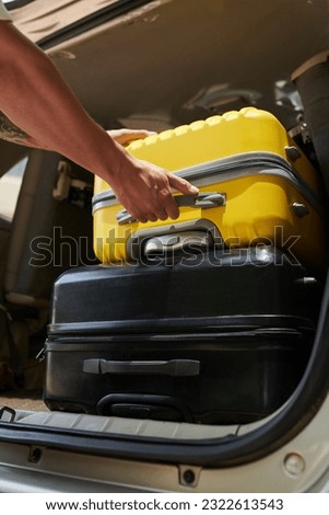 Closeup image of airport transfer driver taking suitcases out of car trunk