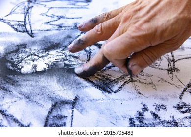 Close-up image of artists hand painting with black graphite crayon. Concept of professions and unusual people