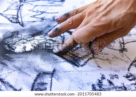 Close-up image of artists hand painting with black graphite crayon. Concept of professions and unusual people