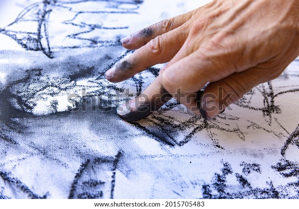 Close-up image of\
artists hand painting with black graphite crayon. Concept of\
professions and unusual\
people