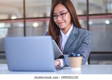 Closeup Image Of An Asian Business Woman Using Digital Tablet And Laptop Computer In Office