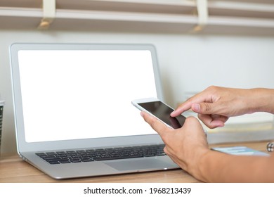 Closeup Image Of Asian Businessman Hand Holding And Using Smart Phone And Checkin Email With Laptop Place On Old Wooden Office Desk At Home.