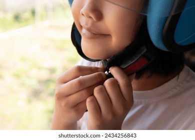 Closeup image of Asian kid smiling and buckling motorcycle helmet. Copy space for text.