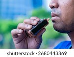 Closeup image of an Asian man using vape or an e-cigarette. Vaping, smoking alternative concept.