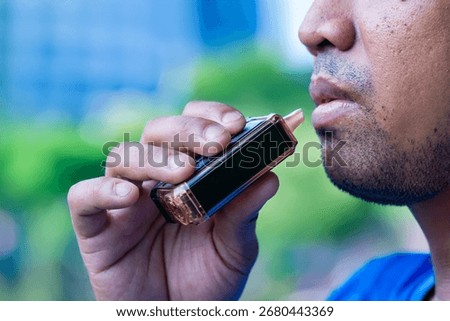 Closeup image of an Asian man using vape or an e-cigarette. Vaping, smoking alternative concept.