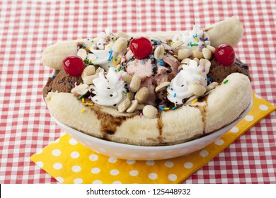 Close-up Image Of A Banana Split Sundae On The White Bowl Over The Red Table Cloth