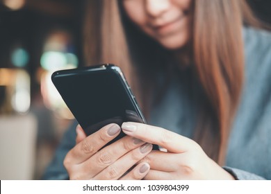 Closeup image of a beautiful Asian woman holding , using and looking at smart phone with feeling happy - Shutterstock ID 1039804399