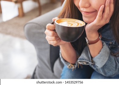 Closeup image of a beautiful asian woman holding and drinking hot coffee in cafe - Powered by Shutterstock