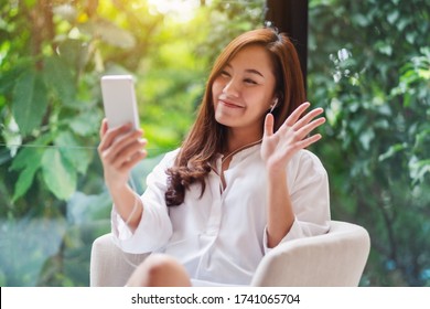 Closeup Image Of A Beautiful Asian Woman Waving Hands While Using Mobile Phone For Video Call At Home