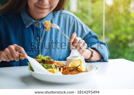 Closeup image of a beautiful asian woman eating fish and chips on table in the restaurant