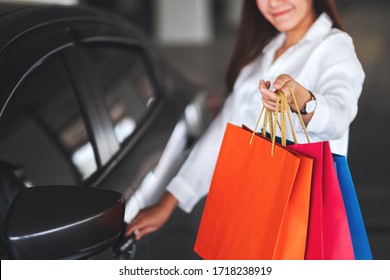 Closeup Image Of A Beautiful Woman Holding And Showing Shopping Bags While Opening Car Door In The Mall Parking Lot