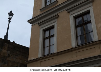 A closeup image of a beautifully detailed building facade highlighting ornate windows and a charming vintage lamp post - Powered by Shutterstock