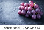 A close-up image of a bunch of ripe red grapes on a dark background. The grapes are fresh, juicy, and look delicious. They are a healthy and nutritious snack, rich in vitamins and antioxidants.