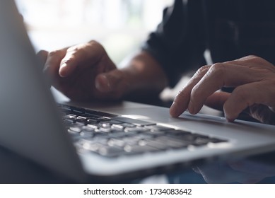 Closeup image of a business man's hands working and typing on laptop computer keyboard with mobile smart phone on wooden table, online working from home, portable office concept