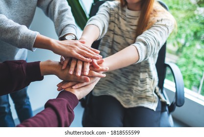 Closeup image of business team standing and joining their hands together in office - Shutterstock ID 1818555599