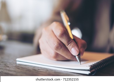 Closeup image of business woman writing on blank notebook on wooden table background