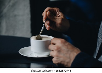 Closeup image of a businessman`s hands with coffee. Closeup ,Selected focus of man hand holding and stirs sugar in a white cup of coffee ,relaxtion tine concept. - Powered by Shutterstock